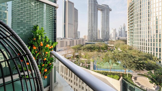 A high-rise building with a view of a cityscape, including other tall buildings and a tennis court. - Luxury 2BR in Downtown Dubai, Near Burj Khalifa (Downtown)