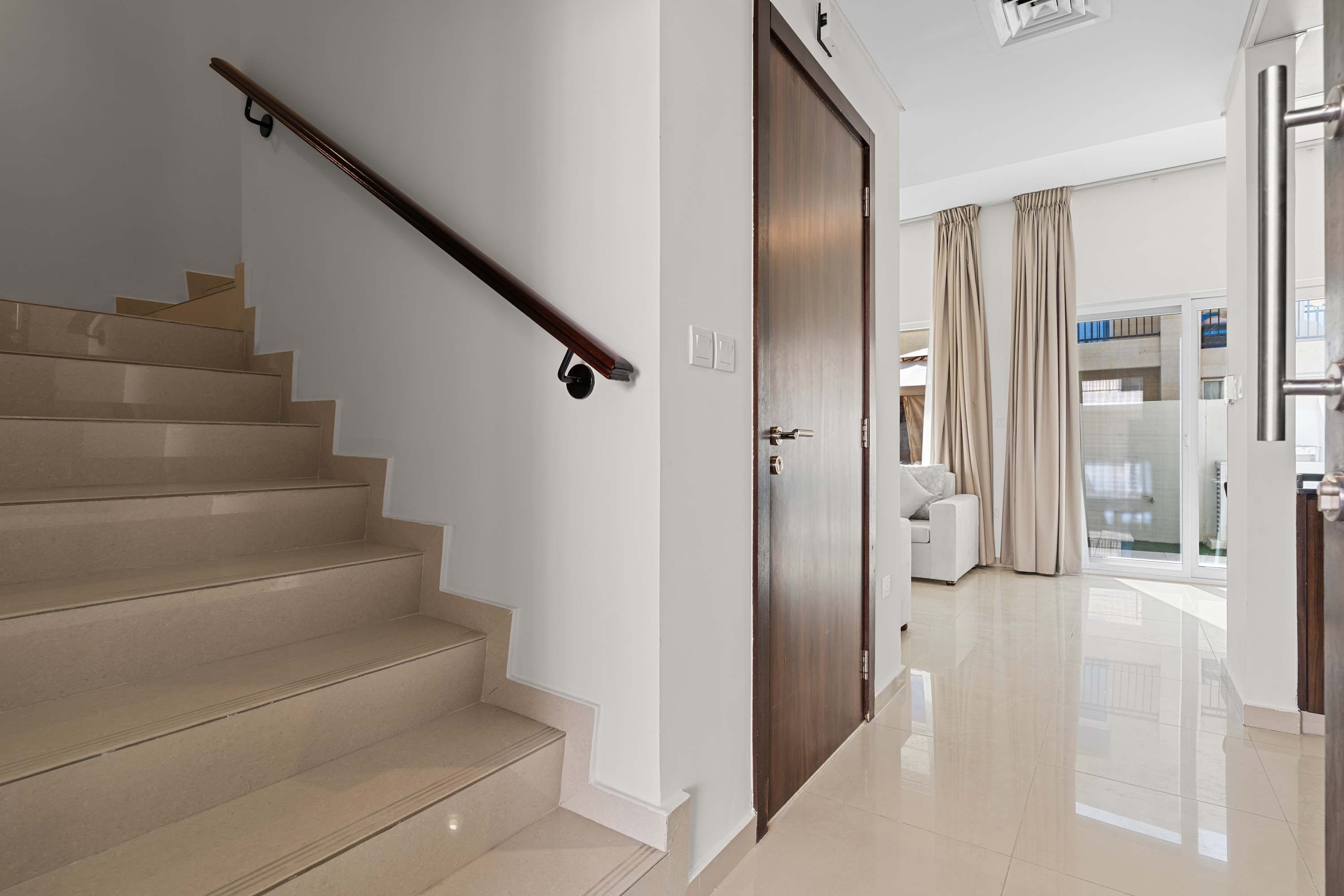 Un escalier avec une rampe, une porte en bois et un mur blanc.