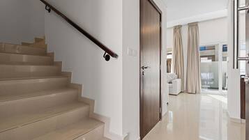 Un escalier avec une rampe, une porte en bois et un mur blanc.