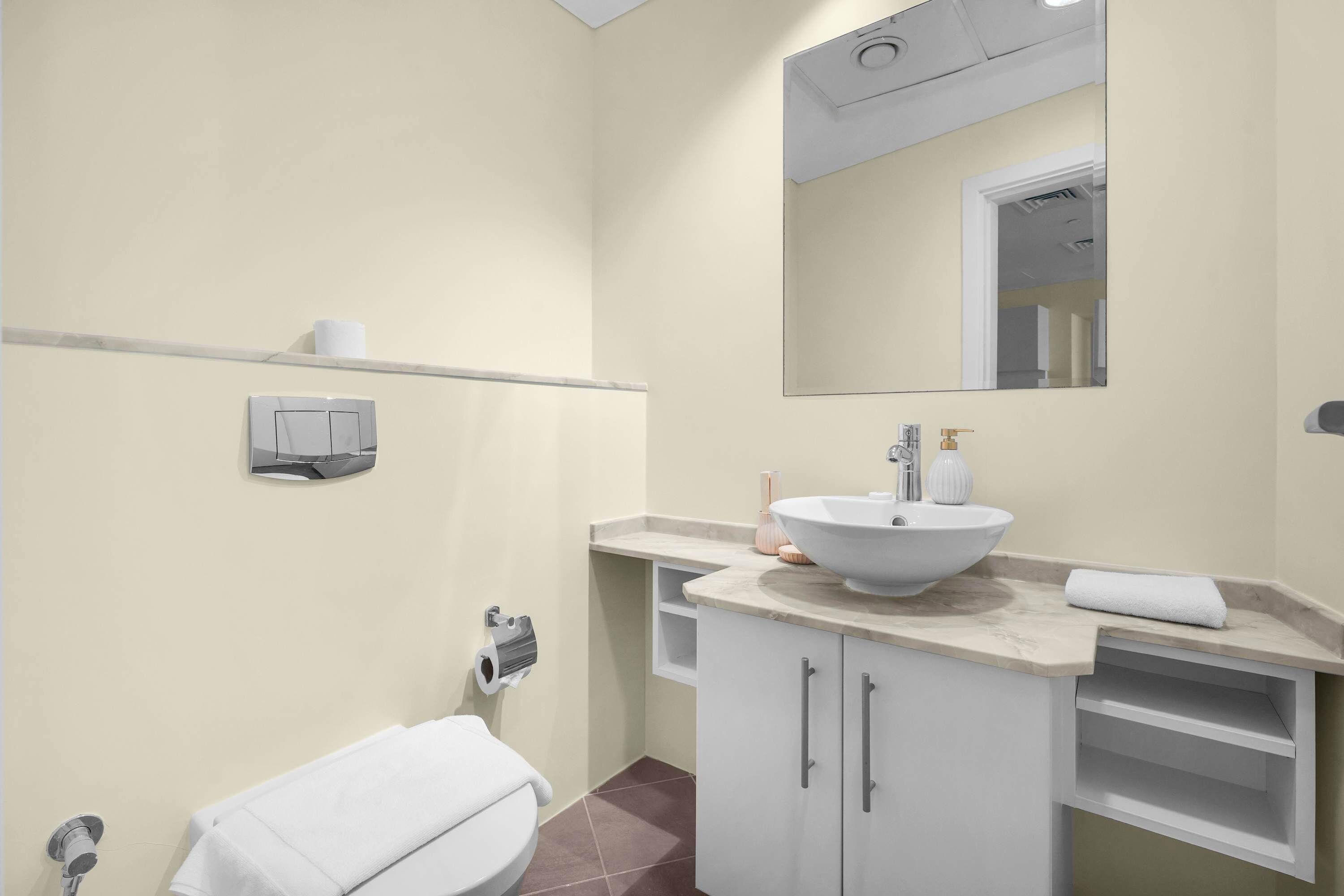 Ein Badezimmer mit weißem Waschbecken, einem Spiegel, einer Toilette und einem Handtuchhalter.