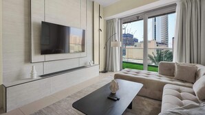 A modern living room with a flat-screen TV, a sofa, a coffee table, and a large window with curtains. - Stylish 2BR w Study and City Views (Dubai Marina)
