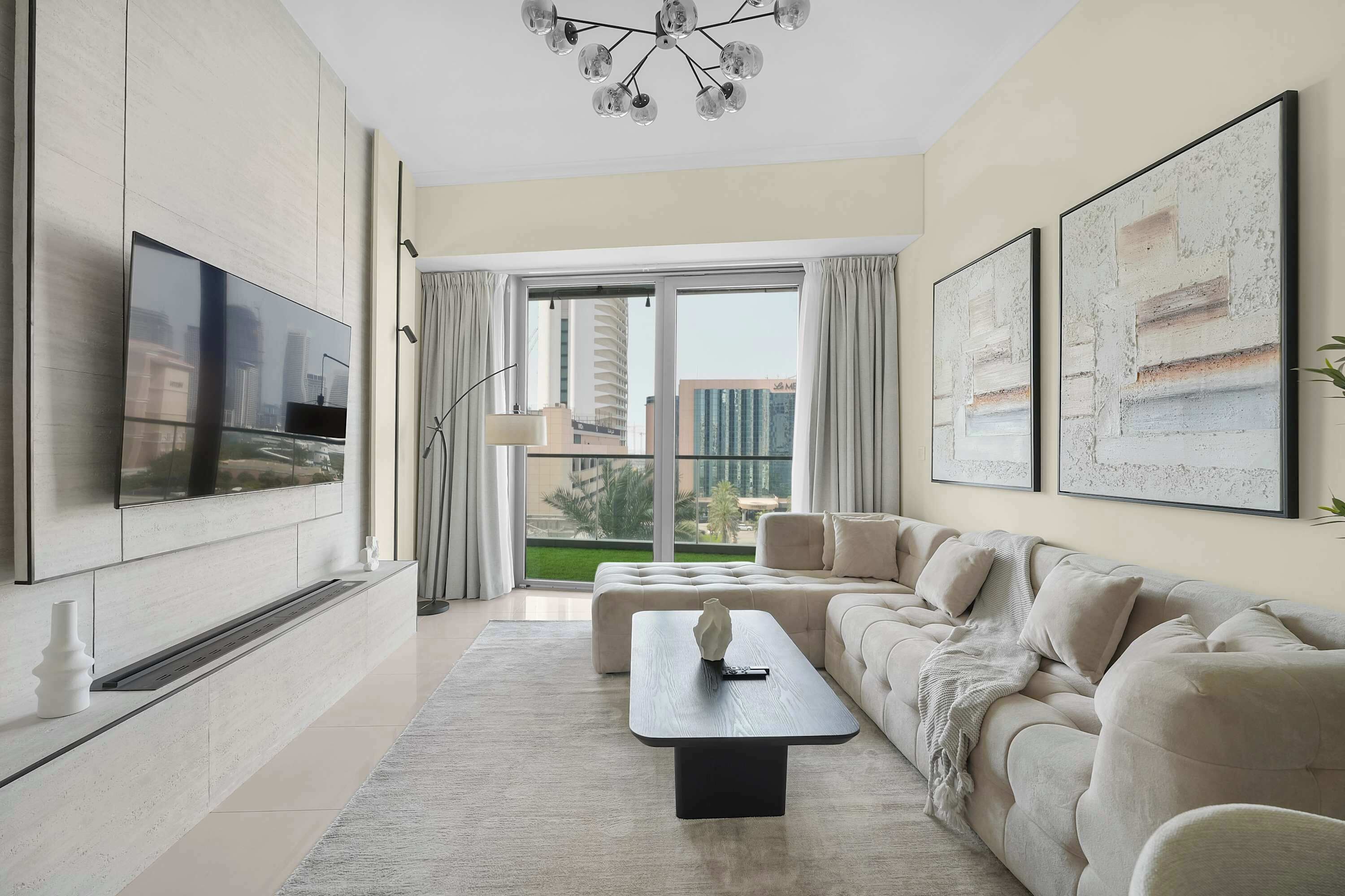 Een moderne woonkamer met een flatscreen-tv, een hoekbank, een salontafel en een groot raam met uitzicht op de stad.