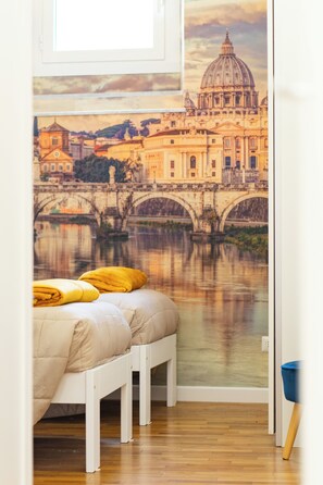 A bedroom with a bed, pillows, a wooden floor, and a wall mural of a bridge over a river. - Domus in Trastevere - 2 bedrooms 2 bathrooms (Roma)
