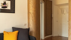 Un salon moderne avec un canapé foncé, un parquet en bois et des œuvres d’art encadrées accrochées au mur.