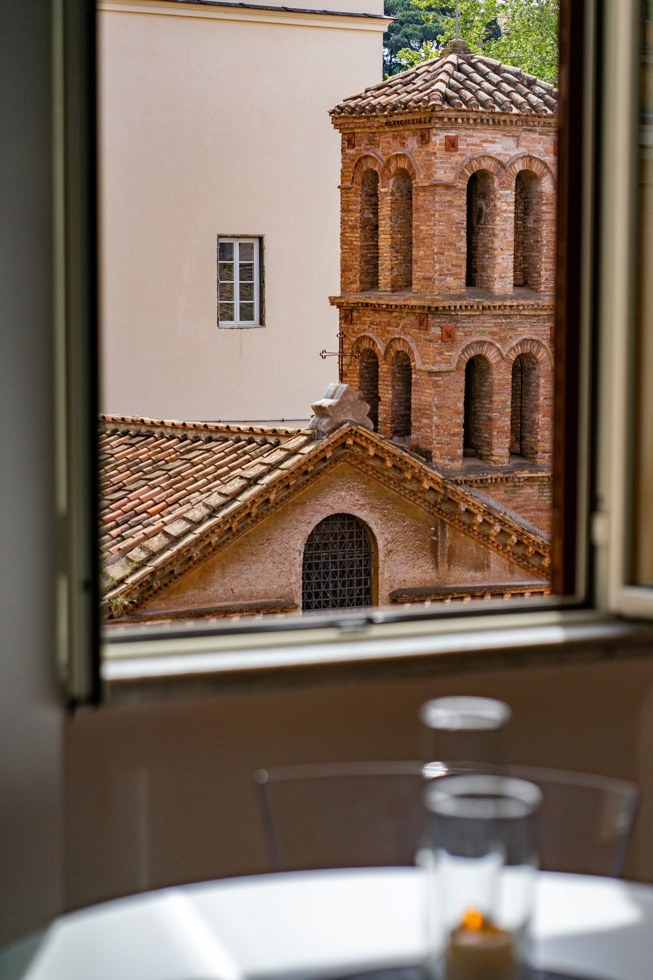 A window view of a brick building with arched windows and a tiled roof.