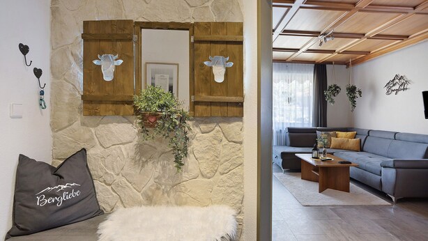 Un salon avec un mur en pierre, une porte en bois ornée d’une tête de vache, un canapé et une table basse.
