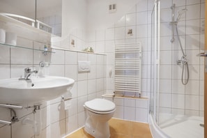 Ein Badezimmer mit weiĂem Waschbecken, WC und Dusche.