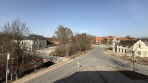 Une rue pavée bordée de bâtiments historiques, un passage piéton et un ciel dégagé.