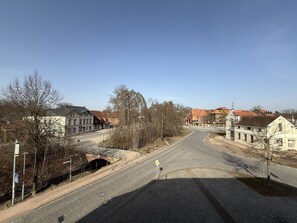 Eine Kopfsteinpflasterstraße mit historischen Gebäuden, einer Fußgängerüberwege und blauem Himmel.