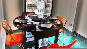 Uma sala de jantar com mesa posta para dois, cadeiras e vista para uma paisagem montanhosa pela janela.