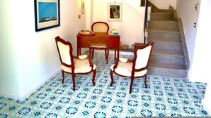 Uma área de refeições com mesa, cadeiras, escada e piso estampado.