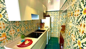 Uma cozinha estreita com uma ilha central, paredes estampadas e chão de azulejos.