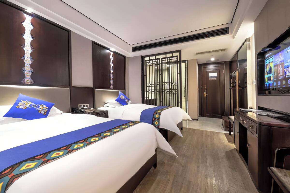 Een hotelkamer met twee bedden, een bureau, een televisie en een kledingkast.