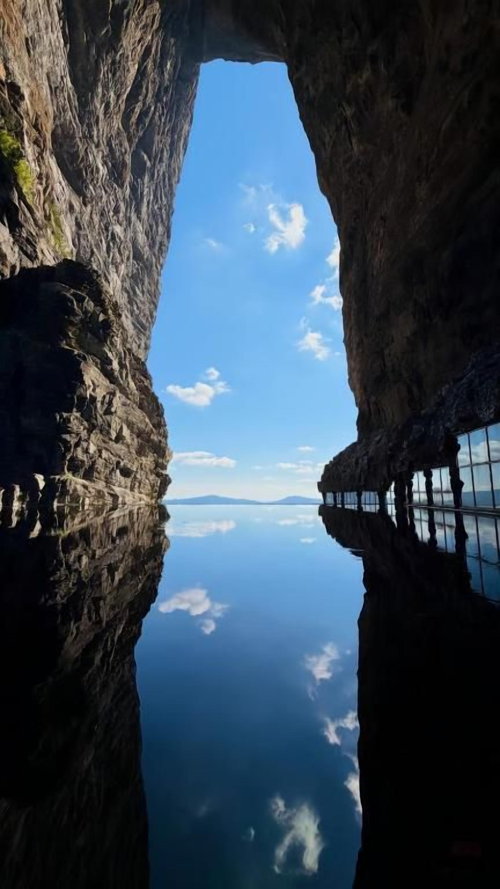 A natural rock formation with a clear sky and calm water below.