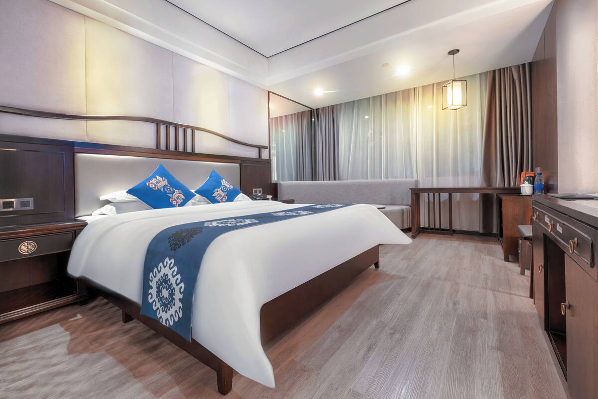 Een hotelkamer met een groot bed, een bureau en een zithoek.