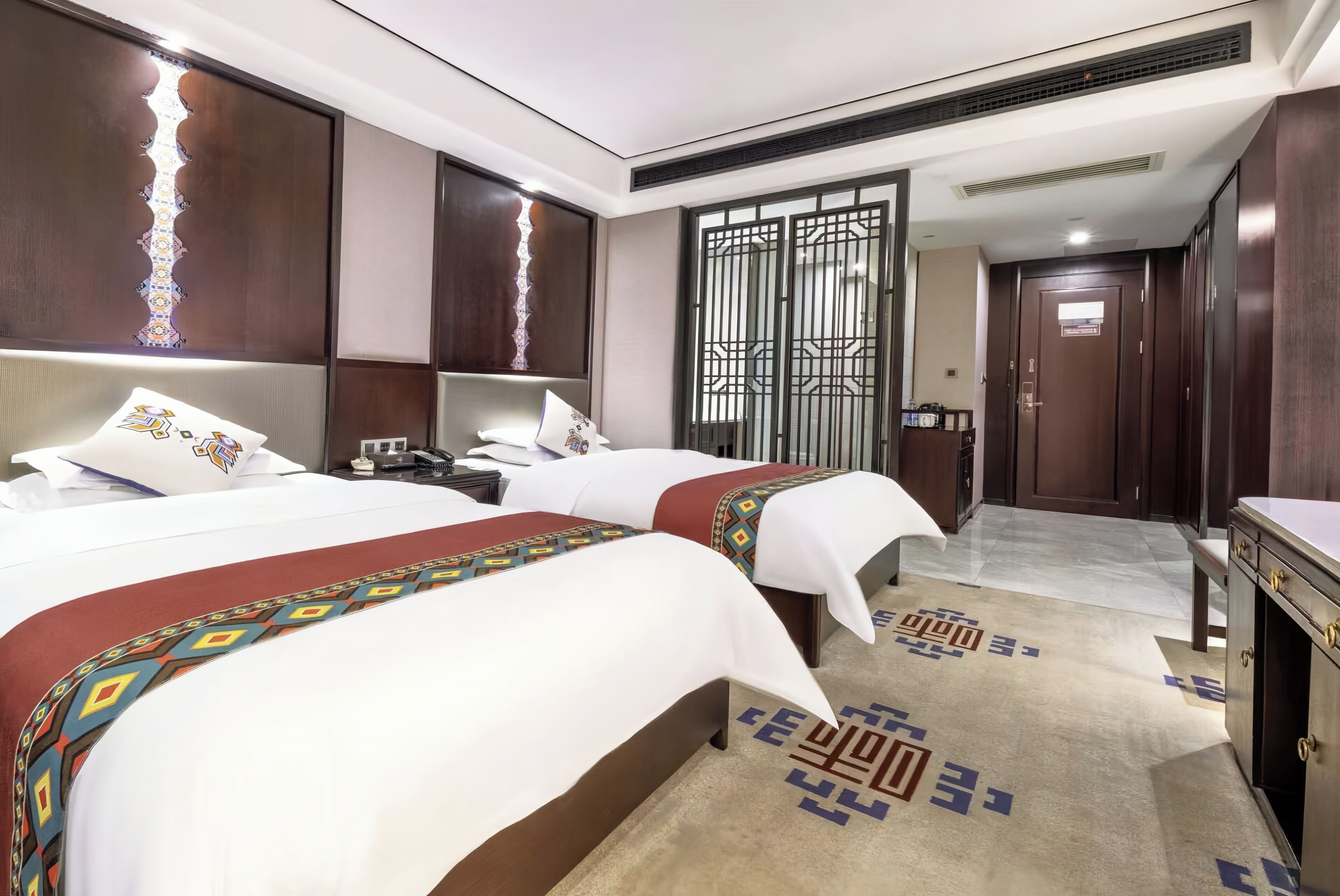 Habitación de hotel con dos camas, un escritorio, un armario y un baño.