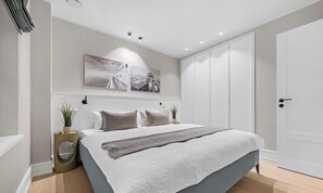 Une chambre à coucher avec un lit, une grande fenêtre, une armoire et un tableau accroché au mur.