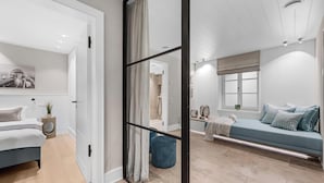 Un dormitorio moderno con una cama, un sofá azul, una ventana y una zona de ducha.
