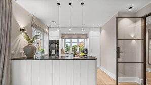 Una cocina moderna con una isla central, electrodomésticos integrados y un amplio ventanal.