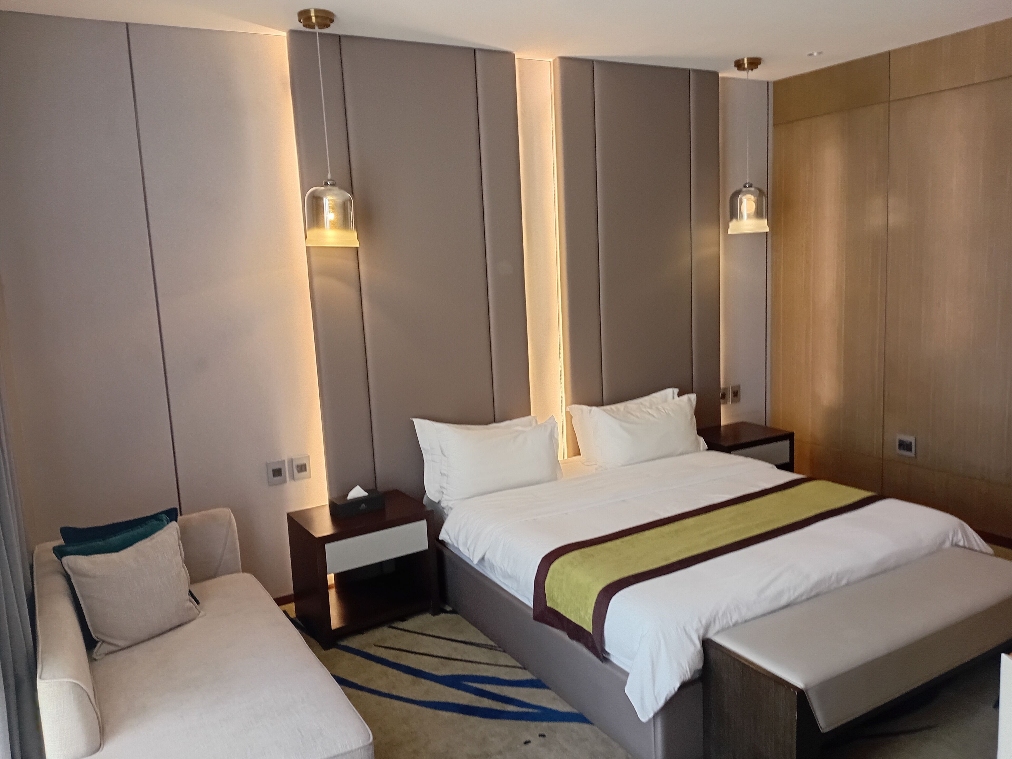 Ein Hotelzimmer mit einem großen Bett, Nachttischen, einer Couch und einem dekorativen Teppich.