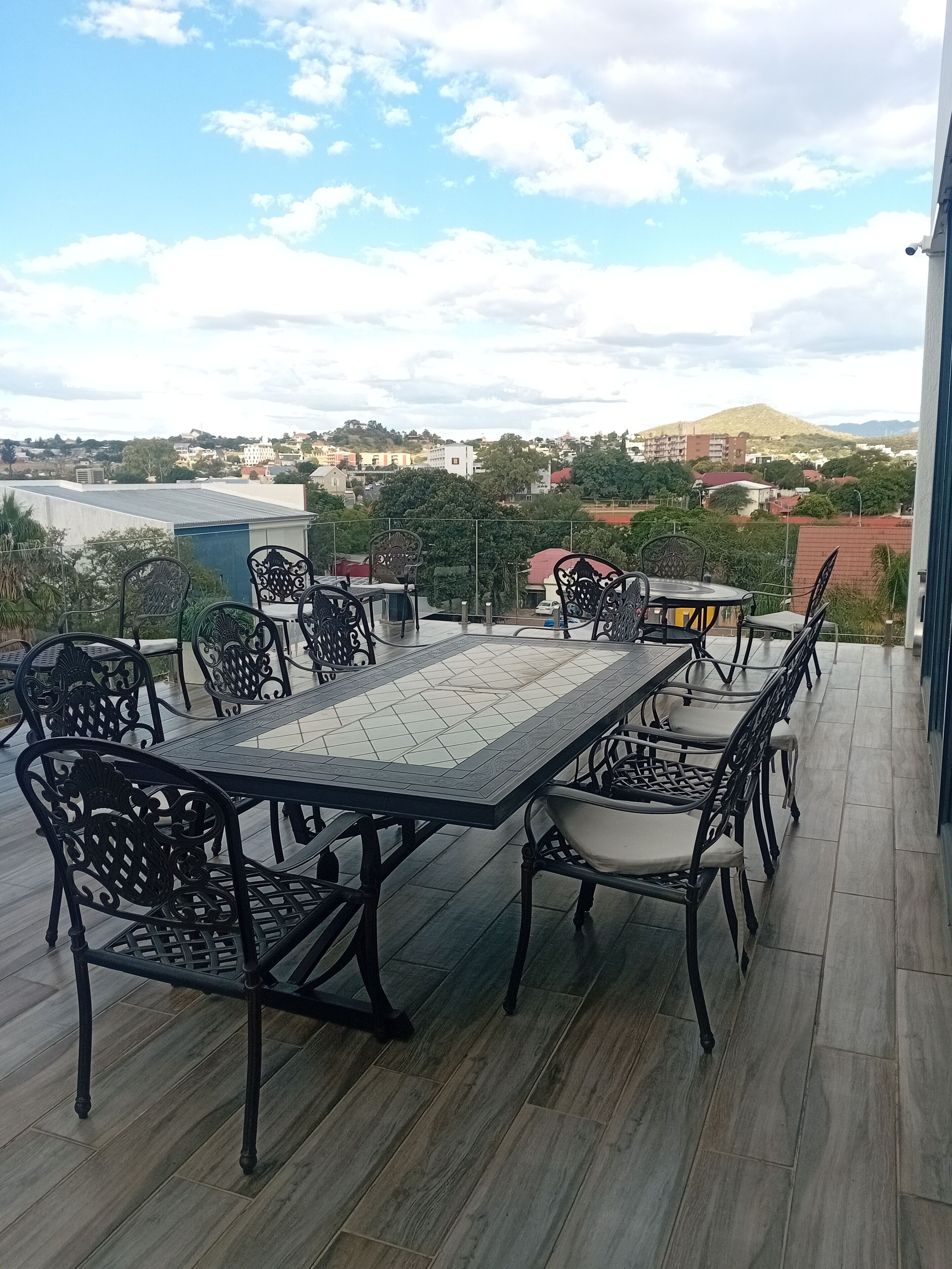 Una terraza en la azotea con una mesa y sillas, vista del paisaje urbano y cielo despejado.