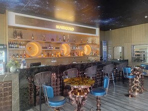A bar area with a 'MARIGOLD' sign, round tables, and blue chairs. - Marigold Hotel  (Windhoek)