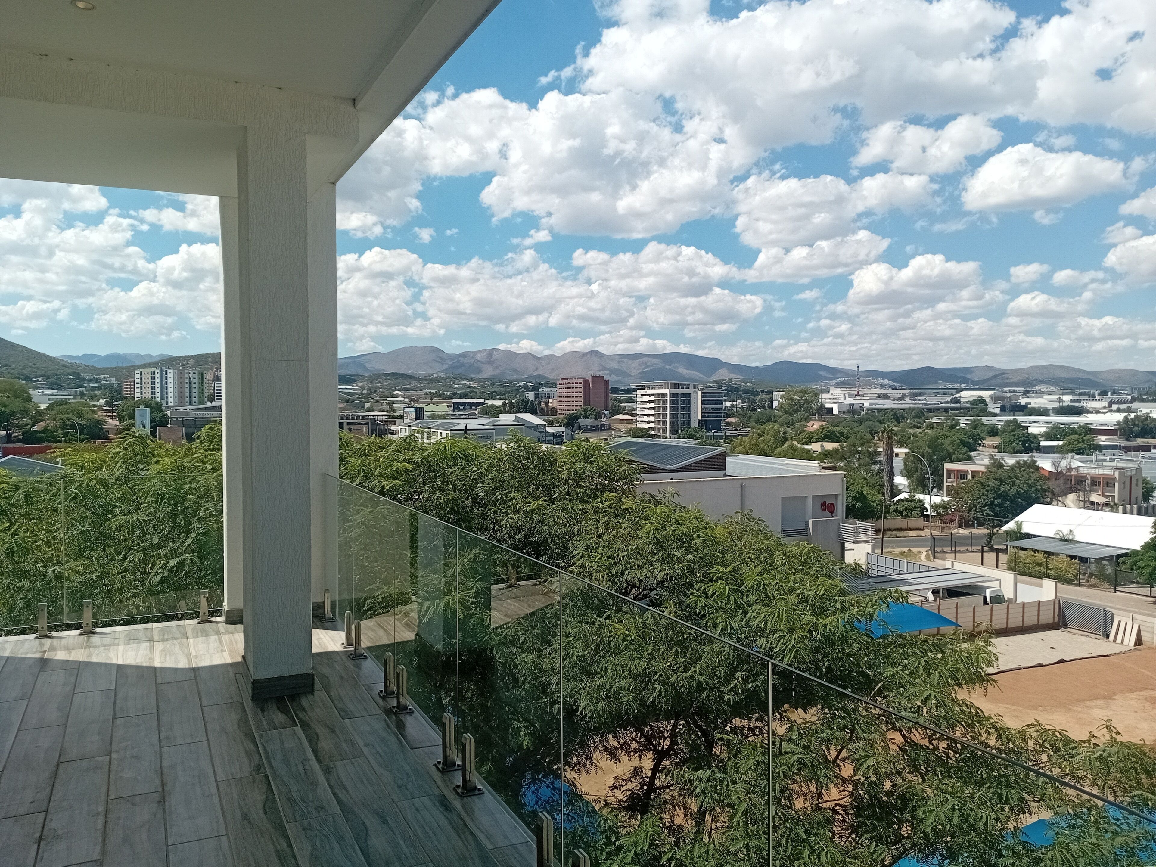 Un balcón con vista a un paisaje urbano, que incluye edificios y montañas.