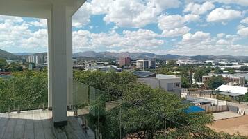 Een balkon met uitzicht op een stadsbeeld, inclusief gebouwen en bergen.