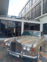Un coche antiguo estacionado frente a un edificio con ventanas amplias y un balcón.