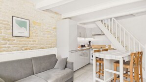 Une cuisine moderne avec des meubles blancs, une table à manger en bois et un escalier.