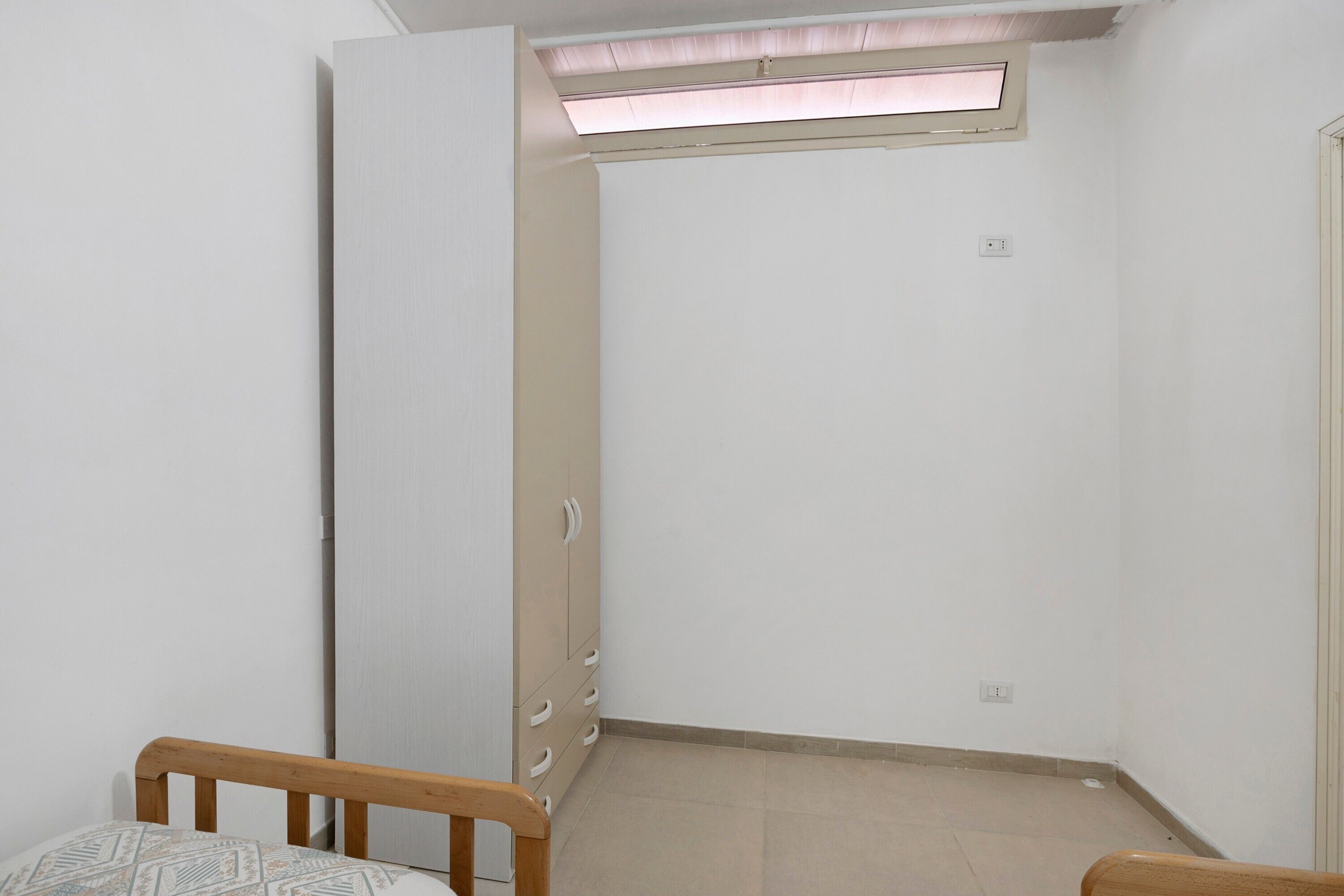 Une pièce comprenant un lit, une armoire, une petite table et une fenêtre.