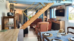 Ein gemütliches Interieur mit einer Holztreppe, einer Essecke und einem an der Wand befestigten Fernseher.