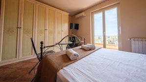 Een slaapkamer met een bed, een kledingkast, een televisie en een balkon.