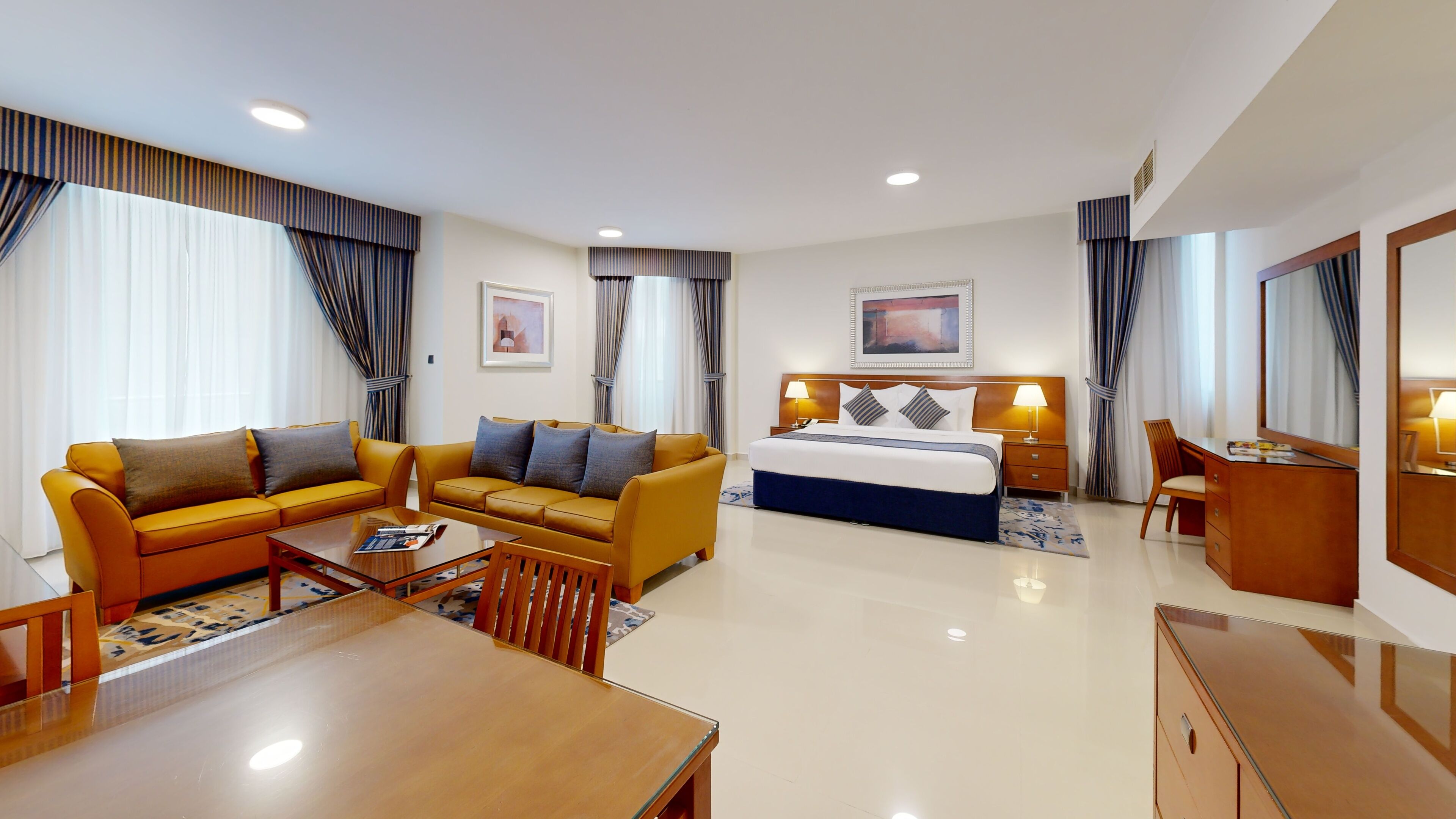 Quarto de hotel com cama, sofá, escrivaninha e cadeira.
