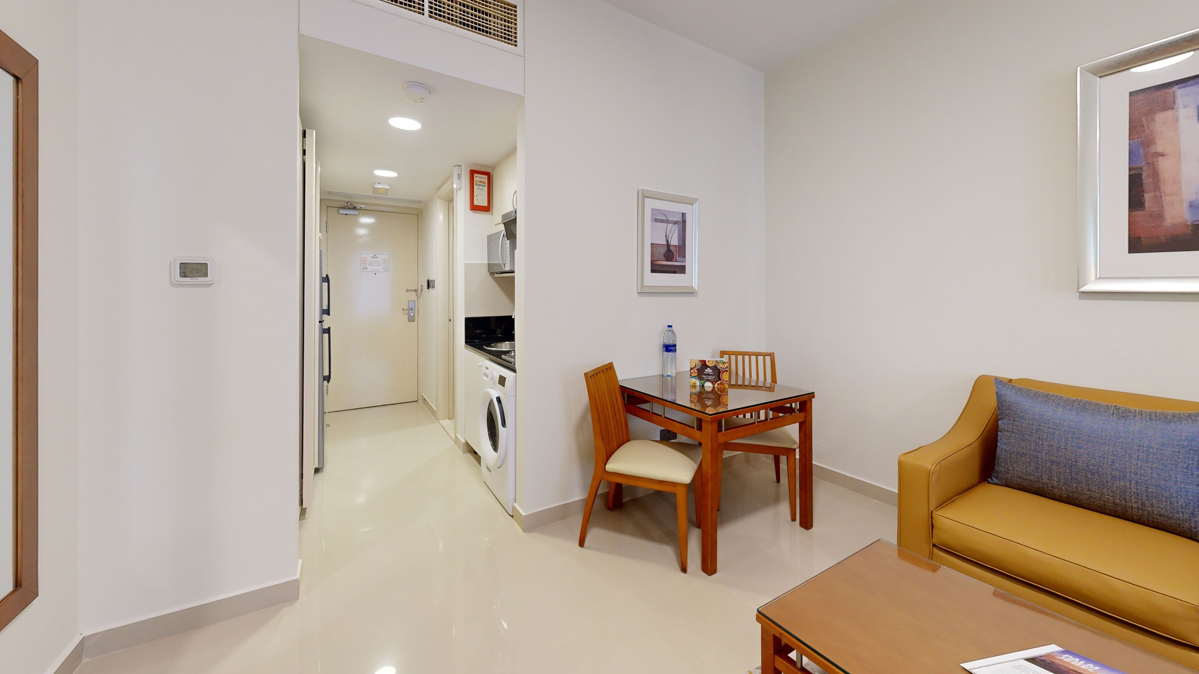 A hotel room with a dining area, kitchenette, and a sofa.