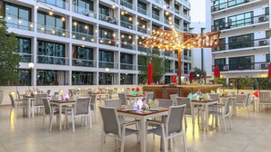 A rooftop dining area with tables, chairs, and a bar. - Golden Sands 5 Hotel Apartment (Dubai)