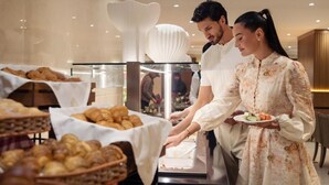A buffet setup with various baked goods and a person serving food. - Golden Sands 5 Hotel Apartment (Dubai)