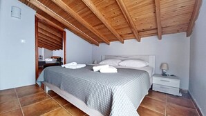 Ein Schlafzimmer mit Holzboden, einem Bett mit weißer Bettwäsche, einem Nachttisch und einem Fliesenboden.