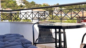 Eine Dachterrasse mit einem Bett, einem Tisch und Stühlen.