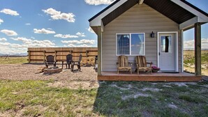 A small cabin with a porch, a wooden deck, and outdoor seating. - Stargazing Cabin Near Glacier w/ Loft & Fire Pit (Augusta)