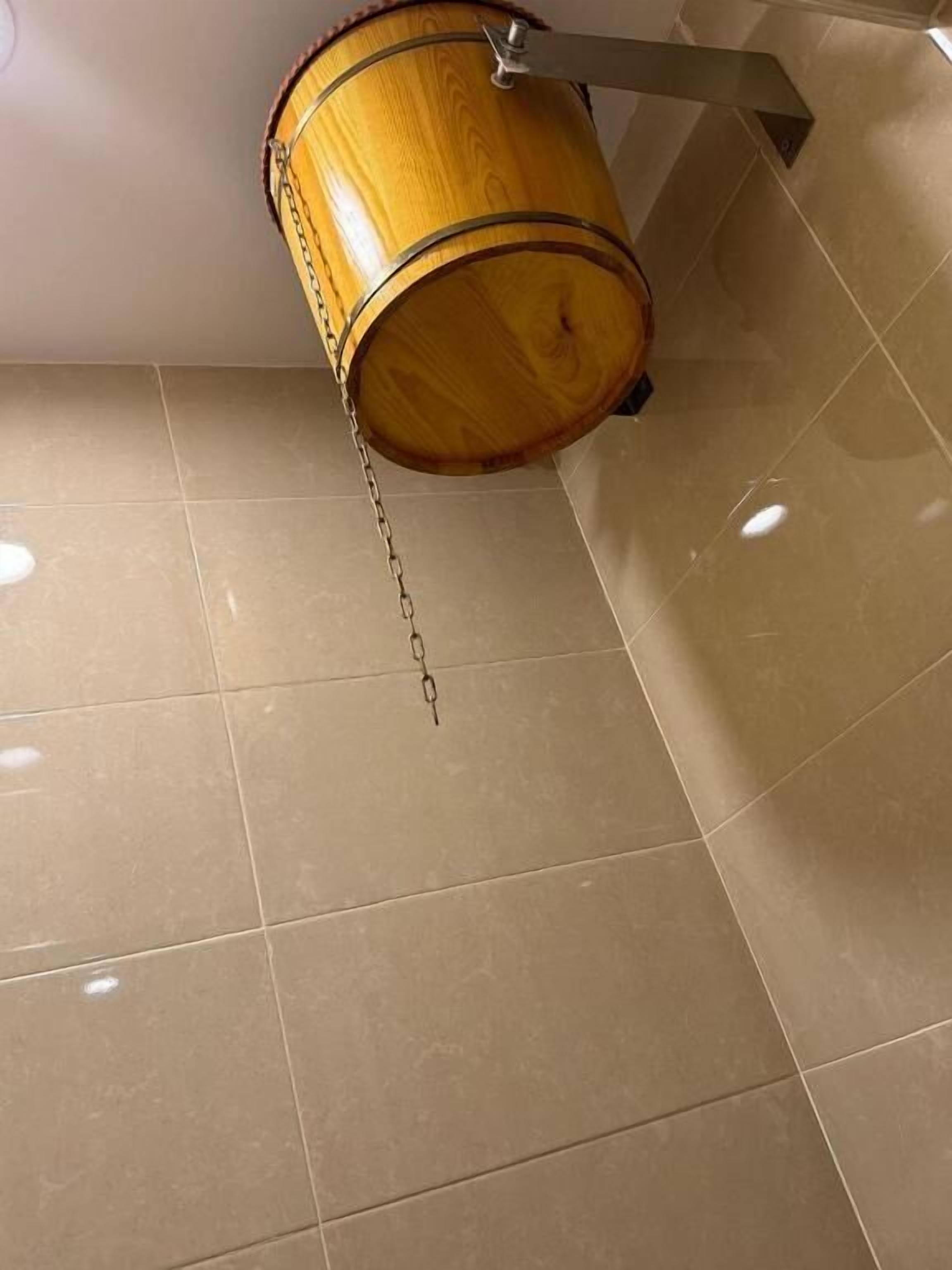 A wooden barrel hanging from a metal fixture on a tiled floor.