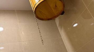 A wooden barrel hanging from a metal fixture on a tiled floor.