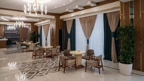 Un vestíbulo amplio con candelabro, mesas redondas y asientos cómodos.