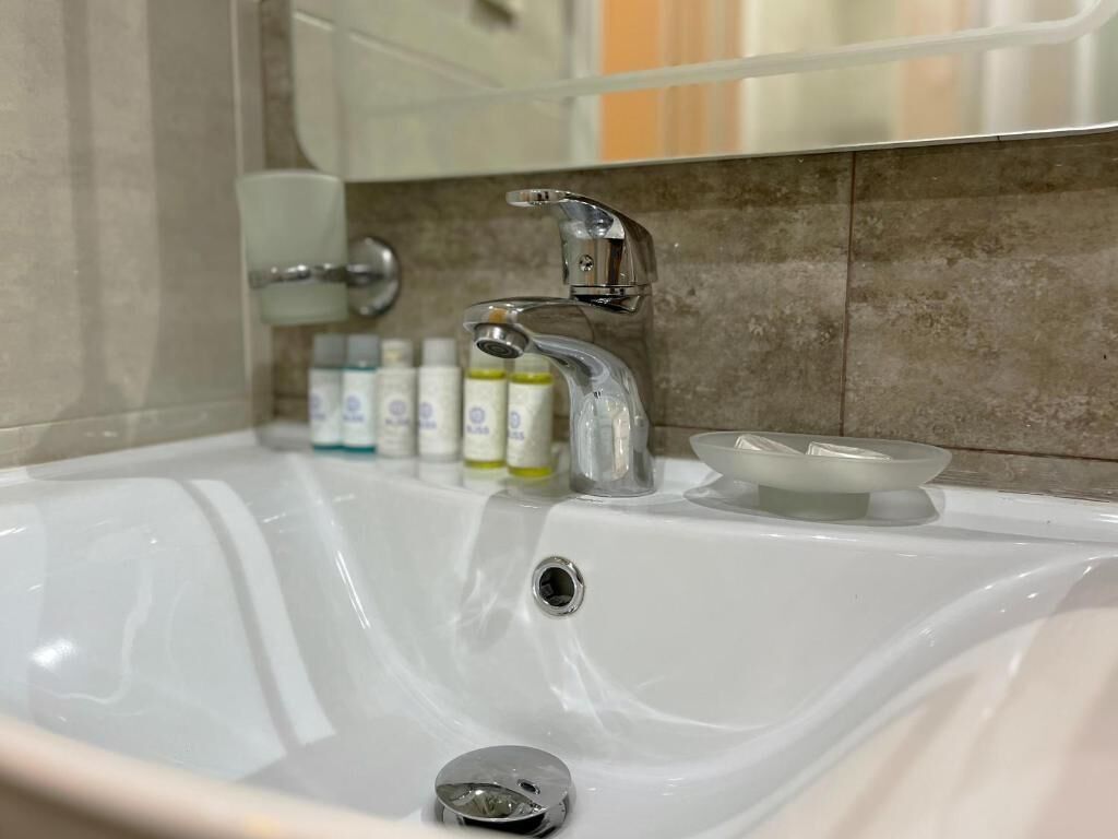 A bathroom sink with a chrome faucet, a soap dish, and a mirror above.