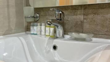 A bathroom sink with a chrome faucet, a soap dish, and a mirror above.