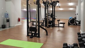 Un gimnasio con equipo de ejercicio, dispensador de agua y extintor.