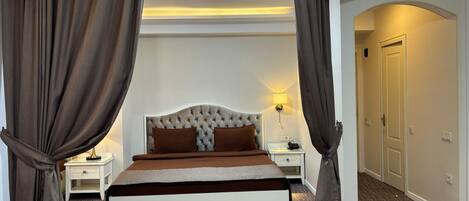Une chambre à coucher avec un grand lit, deux tables de chevet, une lampe et une porte.