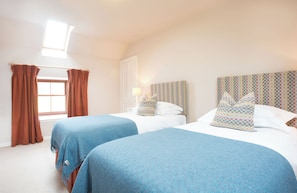 A hotel room with two beds, a window with curtains, a lamp, and a checkered headboard. - Holstein Cottage - The Dairy at Daviot (Daviot)