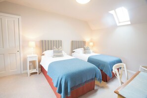 A bedroom with two beds, a small table, and a chair. - Holstein Cottage - The Dairy at Daviot (Daviot)