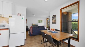 Une cuisine compacte équipée d’un réfrigérateur, d’un four à micro-ondes et d’une table à manger avec des chaises. On y trouve également un canapé et une fenêtre avec vue.